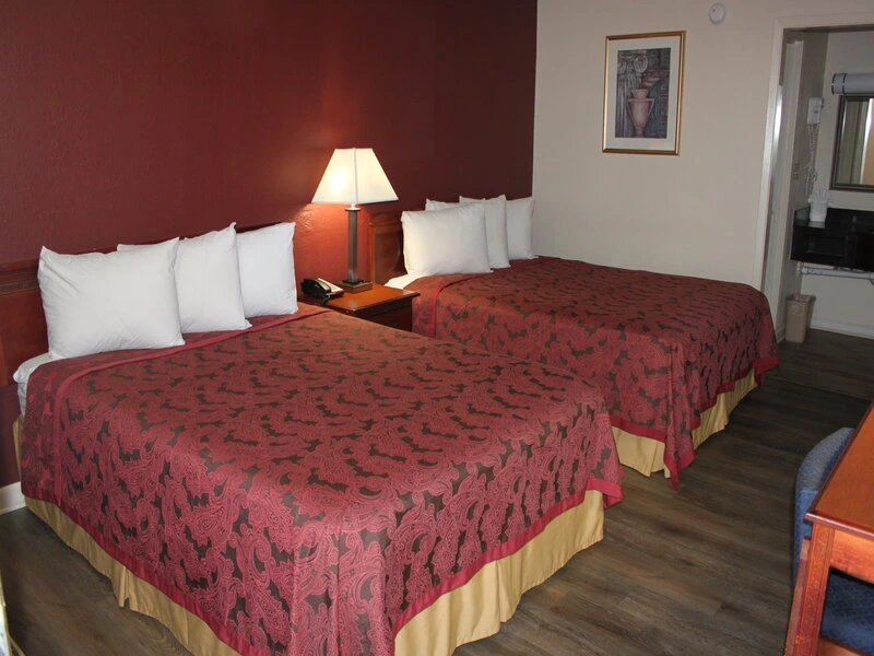 Hotel room with two queen beds featuring red paisley bedspreads and white pillows